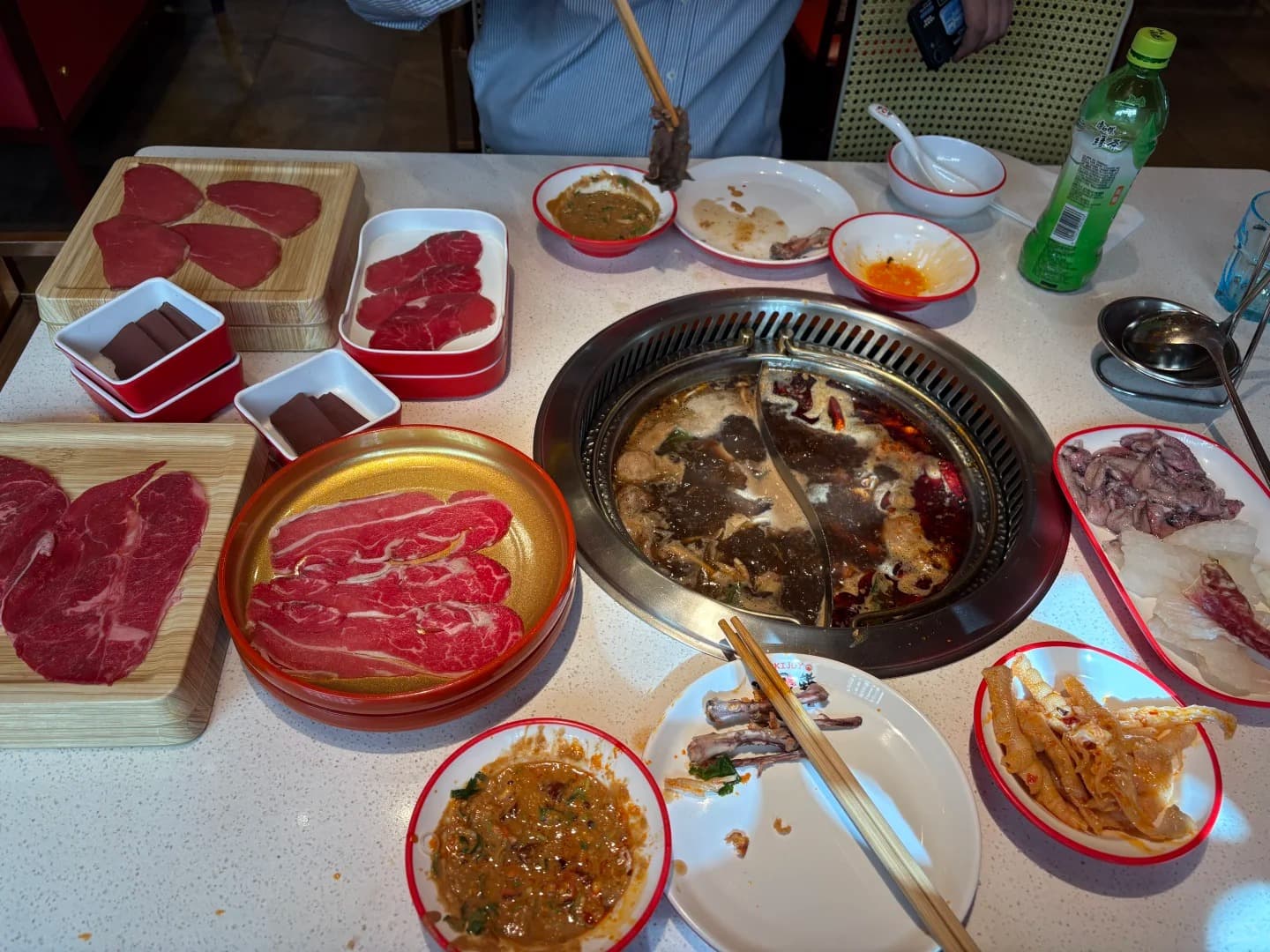 Hotpot table at Sukijoy with split pot, sliced meats, and dipping sauces